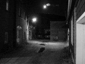 A black and white photo of an alley at night.