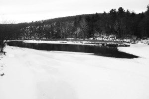 A black and white photo of a river in the snow.