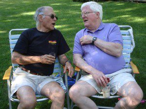 Two older men sitting in lawn chairs.