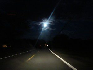 Empty two-lane road beneath glowing moon