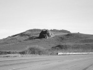 A black and white photo of a hill on the side of a road.