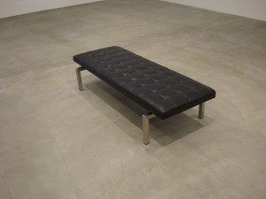 A black leather bench on a concrete floor.