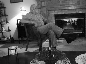 A man sitting in a chair in front of a fireplace.