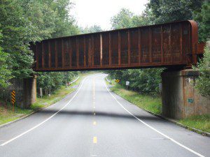 A rusty train bridge over a road.