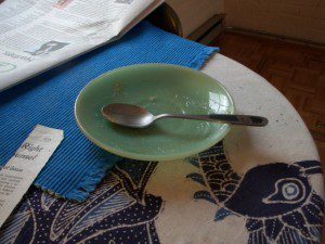 A green bowl on a table next to a newspaper.