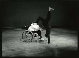 A man in a wheelchair doing a handstand.
