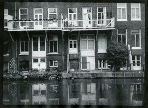 A black and white photo of a row of houses on a canal.