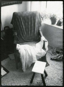 A black and white photo of a chair in front of a window.