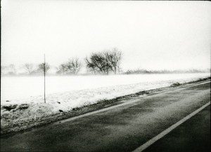 A black and white photograph of a snowy road.