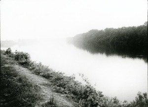 A black and white photo of a river in the fog.