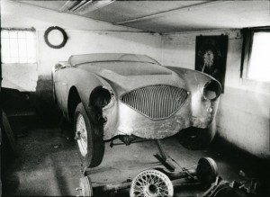 An old car is being worked on in a garage.