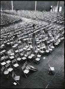 A black and white photo of empty chairs in a large room.