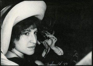 A woman in a hat is holding a camera.