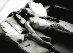 A man laying on a bed with his shirt off.