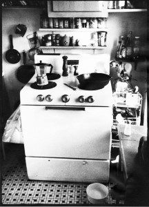 A black and white photo of a stove in a kitchen.