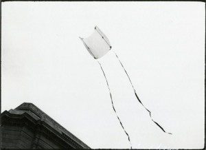 A black and white photo of a kite flying in the air.