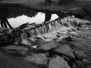 A black and white photo of a waterfall in a park.