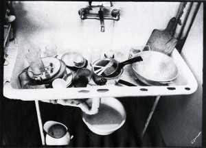A black and white photo of a sink with utensils on it.