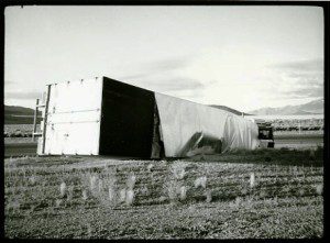 A black and white photo of a truck in the middle of a field.