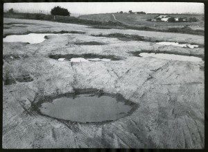 A black and white photo of puddles on the ground.