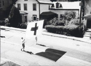An old black and white photo of a group of people carrying a cross.