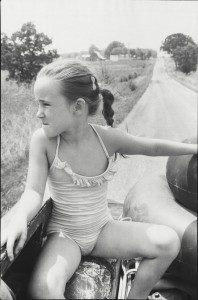 A girl in a bathing suit sitting on the back of a motorcycle.