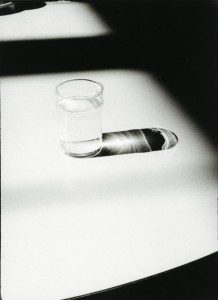 A black and white photo of a glass of water on a table.