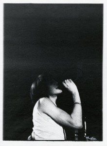 A black and white photo of a woman singing into a microphone.