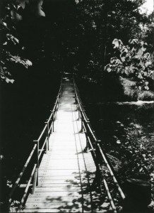 A black and white photo of a wooden bridge.