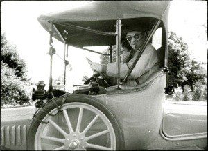 Black and white image of two people in a vintage car
