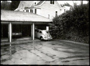 Black and white image of a house with parked cars